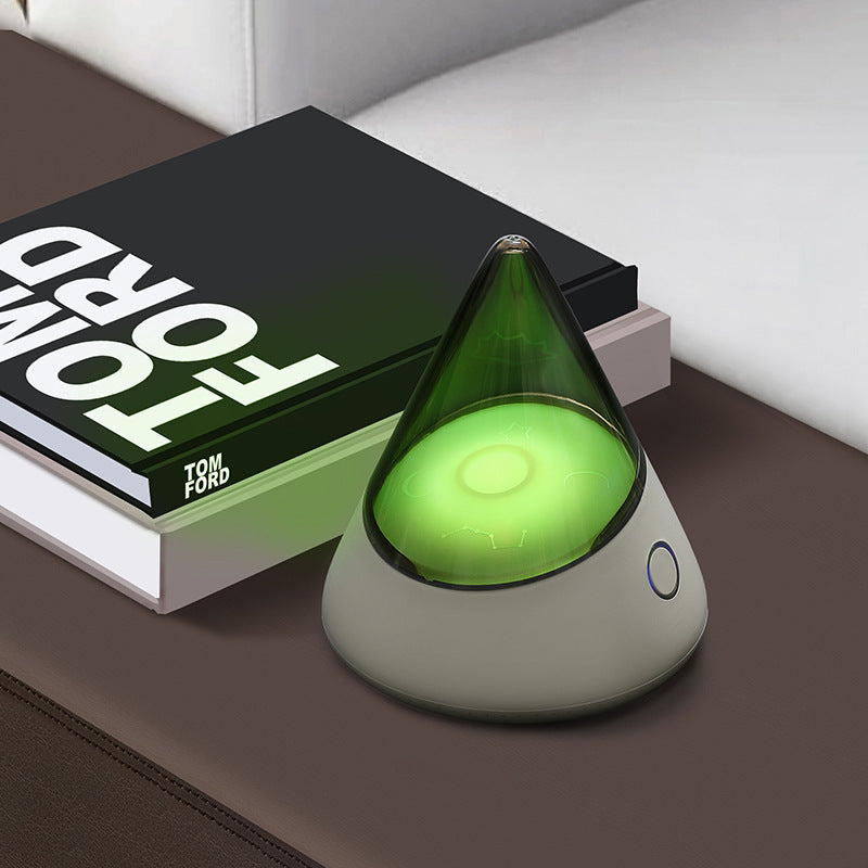 Colorful small night lamp with geometric design and green light on table next to books