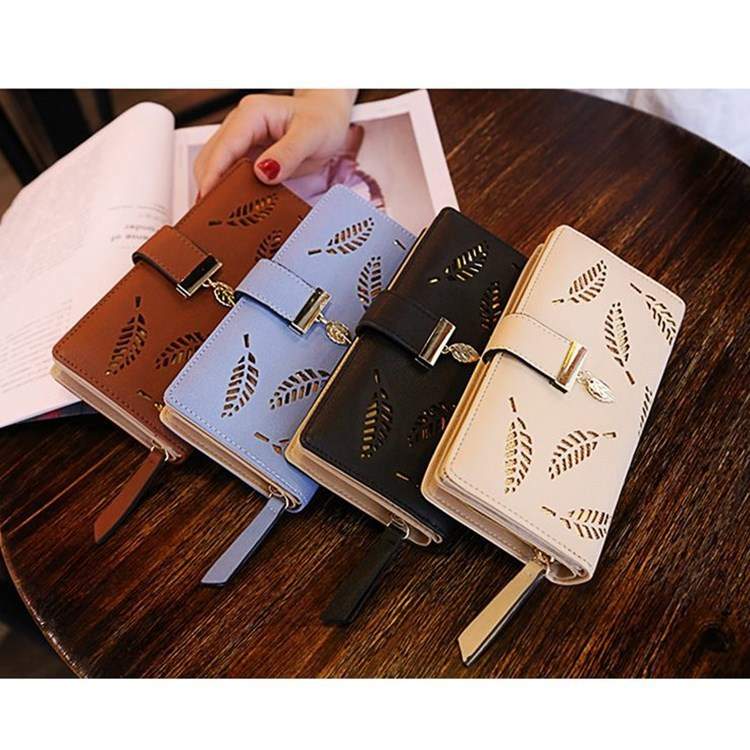 Women's leather wallet purse with leaf cutout design in multiple colors on wooden table
