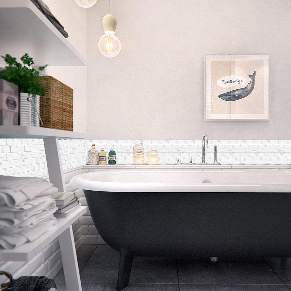 Bathroom wall with white marble look peel and stick tiles behind a black clawfoot bathtub