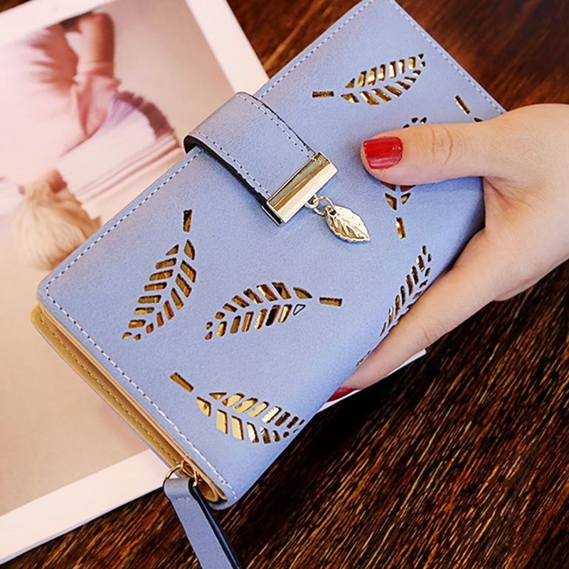 Blue wallet women purse with leaf cutout design and gold leaf charm held in hand