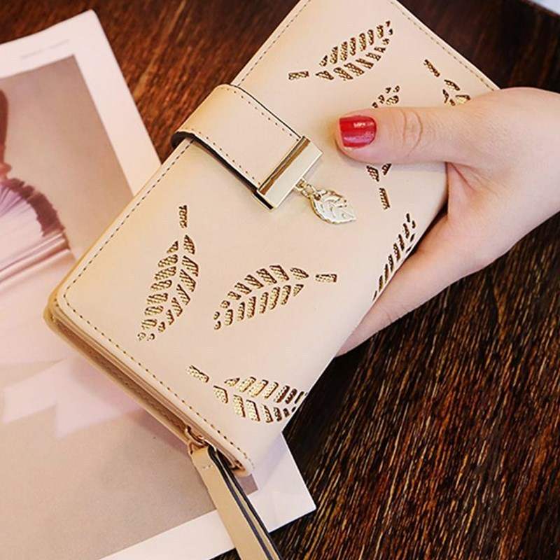 Beige wallet women purse with leaf cutout design and zipper pocket detail held by hand