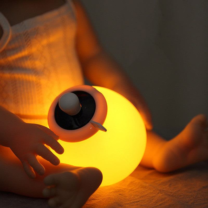 Creative remote control LED bedside night lamp glowing warm yellow in bedroom setting