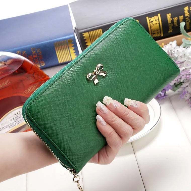 Green ladies wallet handbag with zipper and bow detail in hand