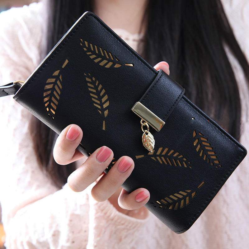 Black women long wallet with hollow leaf design and zipper closure held in hand