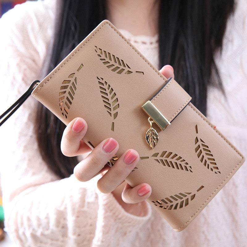 Beige women long wallet with hollow leaf design and zipper closure held in hand