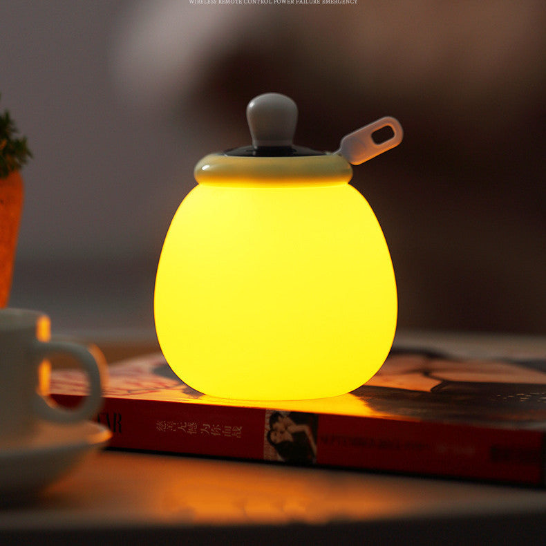 Creative remote control LED bedside night lamp glowing yellow on book in bedroom decor