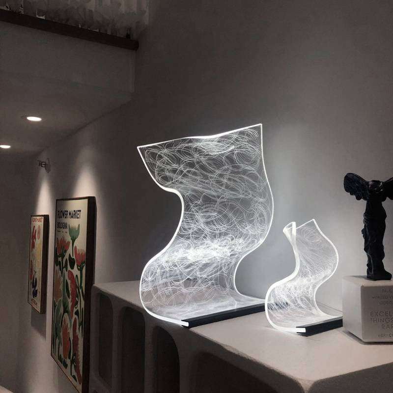 Modern artistic bedside lamp with warm high appearance light in curved abstract design on white shelf