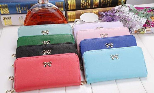 Collection of ladies wallet handbags in various colors with zipper and bow detail made of PU material