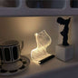 Warm high appearance level bedside lamp glowing softly on shelf next to cup and decorative statue