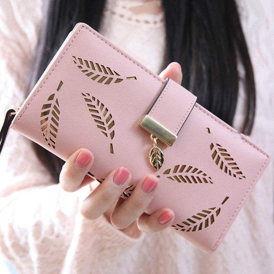Pink women long wallet with hollow leaf design and gold buckle charm, made of soft PU leather with zipper closure.