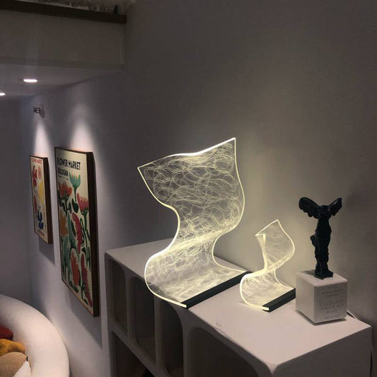Warm high appearance level bedside lamp with artistic abstract design glowing softly on white shelf in modern home decor setting