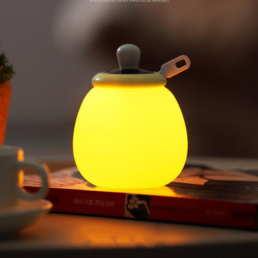 Creative remote control LED bedside night lamp glowing yellow on book in bedroom decor