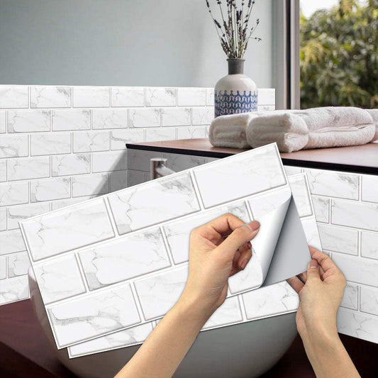 Hands applying white marble look peel and stick PVC tile stickers on bathroom wall next to bathtub with towels and decorative vase