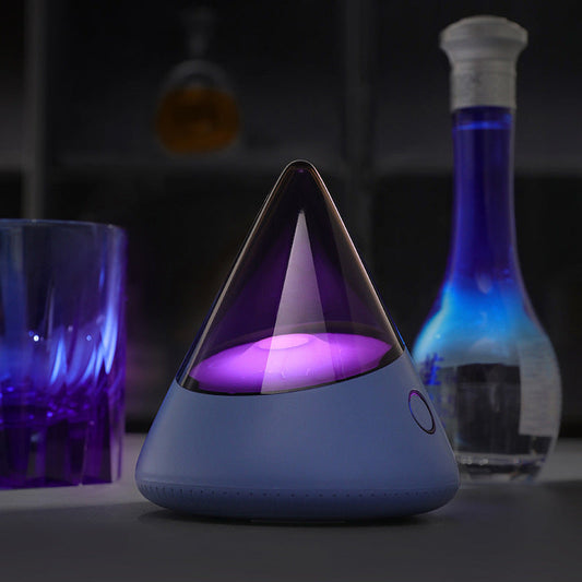 Colorful small night lamp with geometric design glowing purple light on grey base