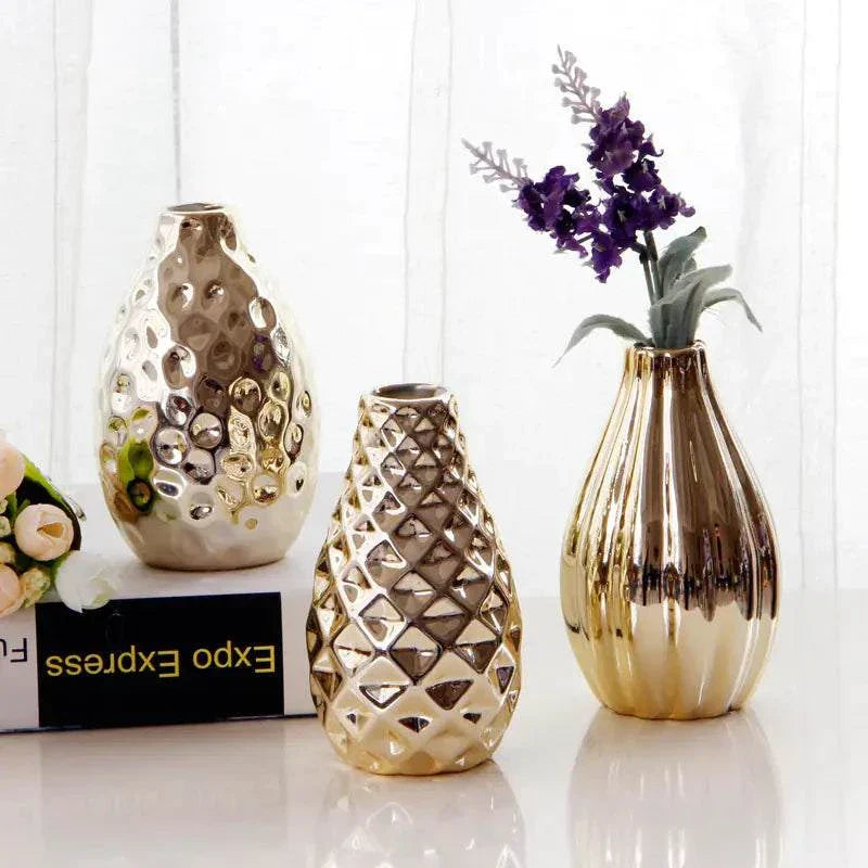 Set of three Nordic ceramic small flower vases with reflective gold finish and textured designs displayed on white surface with flowers.