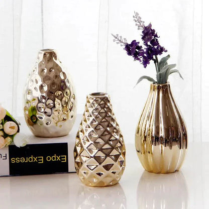 Set of three Nordic ceramic small flower vases with reflective gold finish and textured designs displayed on white surface with flowers.